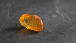 Orange yellow baltic amber stone on gray slate background , lit by the sun  