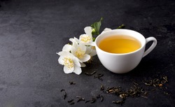 Jasmine flowers and cup of healthy tea  on a black background. Herbal medicine