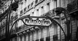Parisian metropolitan (metro, subway) sign in a street during the day. Typical house in the background. Old times, vintage, nostalgia concept. Historic black and white photo. Paris, France. 