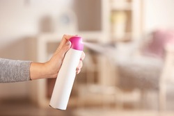 Woman spraying air freshener at home