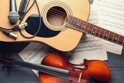 Guitar, violin and music sheets on table, top view