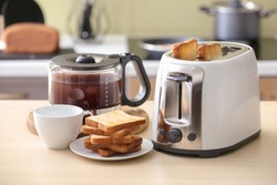 Toaster with bread slices and carafe of hot coffee on table