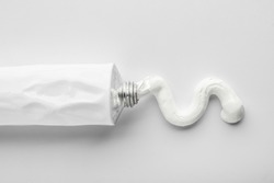 Tube with squeezed paste on white background