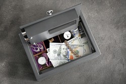 Small modern safe with valuables on grey background