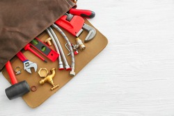 Bag with plumbing tools and items on white table