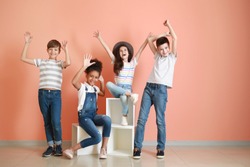 Happy children in jeans near color wall