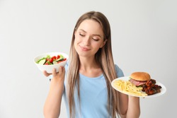 Woman with healthy and unhealthy food on light background. Diet concept