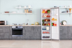 Open big fridge with products in interior of kitchen
