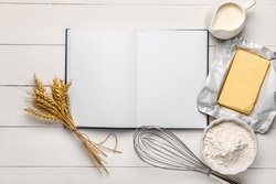 Cook book with products on white wooden background