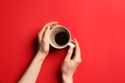 Female hands with cup of hot coffee on color background