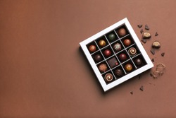 Box with delicious chocolate candies on color background