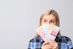 Young woman with color swatches on grey background