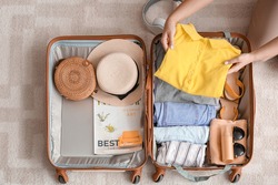 Woman packing suitcase at home. Travel concept