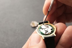 Clockmaker repairing broken watch at table, closeup