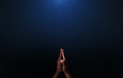 Hands of African-American man praying to God on dark background