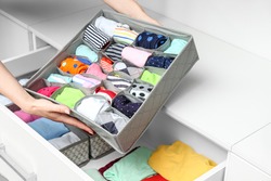 Woman with clean clothes in organizer at home