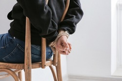 Female hostage with tied hands sitting on chair in room