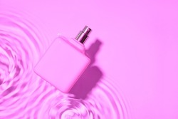 Bottle of perfume in water on color background
