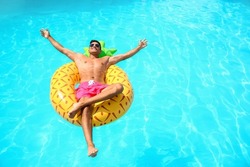 Handsome man with inflatable ring in swimming pool