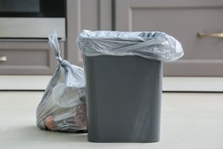 Bag with garbage and rubbish bin in kitchen
