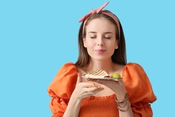 Beautiful young woman with tasty quesadilla on color background