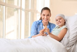 Nurse and little girl with golden ribbon in clinic. Childhood cancer awareness concept