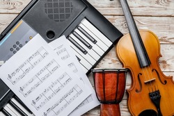 Different musical instruments and music notes on light wooden background, closeup
