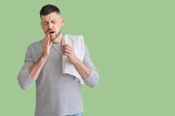 Man with tooth brush suffering from ache on color background