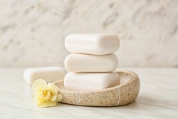 Bowl with soap bars on light background