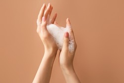Woman washing hands with soap on color background