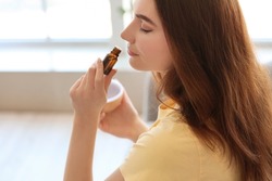 Young woman smelling essential oil, closeup