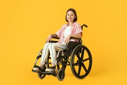 Young woman in wheelchair on color background