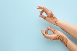 Beautiful female hands with henna tattoo on blue background