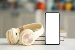 Modern mobile phone, headphones and books on table