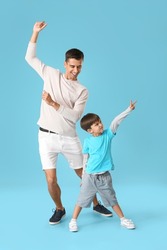 Dancing man and his little son on color background