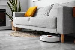 Modern robot vacuum cleaner near sofa in room
