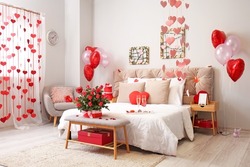 Interior of beautiful bedroom with roses, glasses of champagne and decor for Valentine's Day