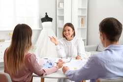 Female wedding planner discussing ceremony with clients in office