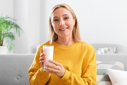 Mature woman with glass of milk at home