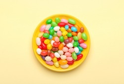 Plate with different jelly beans on beige background