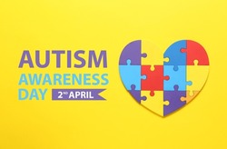 Colorful puzzle pieces in shape of heart on yellow background. World Autism Awareness day