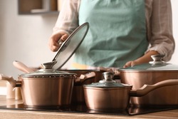 Woman with copper pots cooking in kitchen, closeup