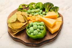 Wooden board with different snacks for St. Patrick's Day celebration on light background