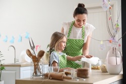 Little girl with her mother preparing Easter cake in kitchen