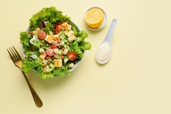 Bowl with tasty vegan Caesar salad and lemon on beige background