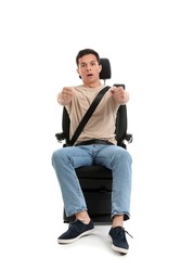 Shocked young man with imaginary steering wheel in car seat on white background