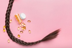 Braided hair strand with pills on pink background
