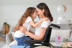 Little girl and her mother in wheelchair on International Women's Day at home