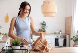 Young woman with bottle and eco bag in kitchen