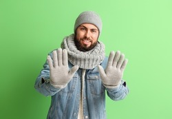 Handsome man in winter clothes on color background